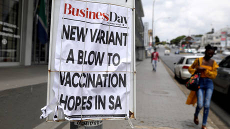 A woman walks past newspaper billboards in Johannesburg, South Africa on February 8, 2021.