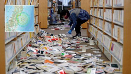 A staff member of library tries to restore books after they fell from book shelves by a strong earthquake at Iwaki City library in Iwaki, Fukushima prefecture, Japan February 14, 2021. © Reuters / Issei Kato