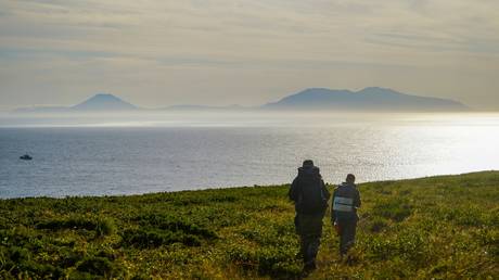 The expedition members look at the Frisa Strait and Iturup Island from the coast of Urup Island. © RIA