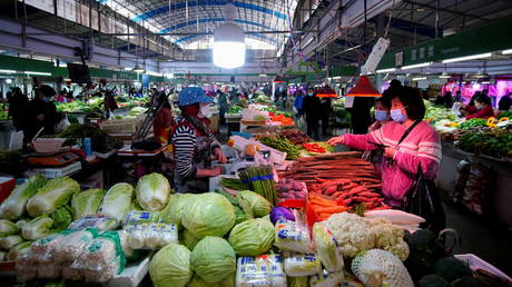 FILE PHOTO: People wearing face masks buy vegetables at a wet market, following an outbreak of the coronavirus disease (COVID-19) in Wuhan, Hubei province, China February 8, 2021
