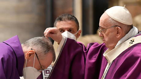 Pope Francis puts ashes on a cardinal's head during the Ash Wednesday mass at St. Peter's Basilica at the Vatican, February 17, 2021.