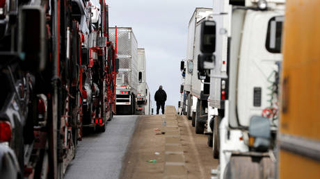 FILE PHOTO: A man stands between trucks waiting in a long queue at the Otay border crossing in Tijuana, Mexico, April 3, © Reuters / Carlos Jasso