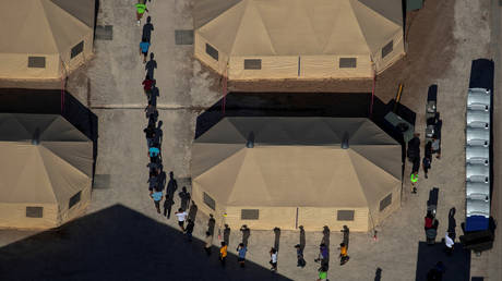 FILE PHOTO: Migrant children are led by staff in single file between tents at a detention facility next to the Mexican border in Tornillo, Texas.