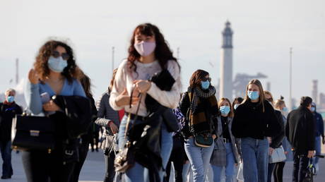 People wearing face masks walk near the beach in Dunkirk, France