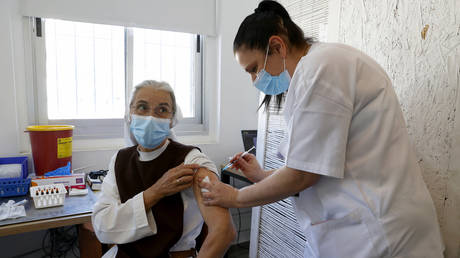 FILE PHOTO: A French nun living in Israel receives a dose of COVID-19 coronavirus vaccine at the Tel Aviv Sourasky Medical Centre February 9, 2021.