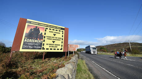 FILE PHOTO: A man and his child rides their horse and cart past a fresh anti-Brexit billboard highlighting the Good Friday peace agreement as they cross the border between Ireland and the United Kingdom on October 27, 2020 in Newry, Northern Ireland.