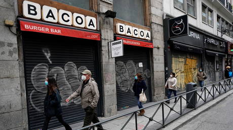 People walk near closed shops amid the coronavirus disease outbreak in Madrid, Spain