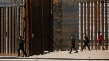 Migrants walk to a gate in the border wall after crossing the Rio Bravo river to turn themselves in to US Border Patrol agents in El Paso, Texas, March 14, 2021 © Reuters / Jose Luis Gonzalez