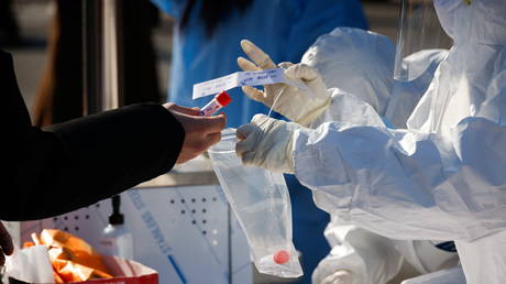 FILE PHOTO. A woman hands her coronavirus test kit over to a medical worker in Seoul, South Korea.