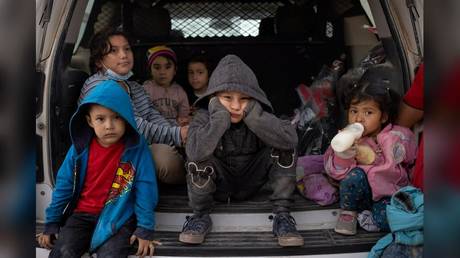 Child migrants take shelter from the rain in the back of a US Border Patrol vehicle on Sunday after crossing the border into Texas.