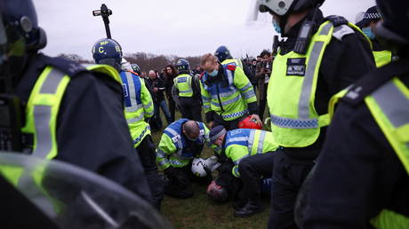 Police officers detain a person during a protest against Covid-19 lockdown in London, Britain March 20, 2021.