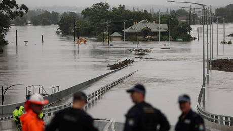Police officers and road workers are seen in front of a submerged structure visible in floodwaters in the suburb of Windsor as the state of New South Wales experiences widespread flooding and severe weather, in Sydney, Australia, March 22, 2021 © REUTERS/Loren Elliott