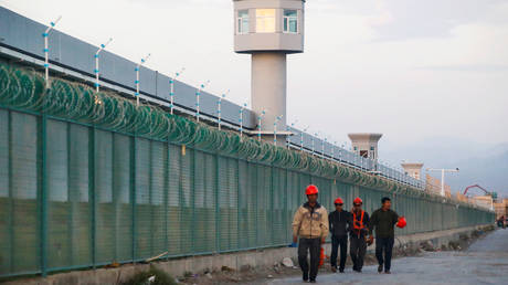 Workers walk by the perimeter fence of what is officially known as a vocational skills education centre in Dabancheng in Xinjiang Uighur Autonomous Region, China (FILE PHOTO) © REUTERS/Thomas Peter/File Photo