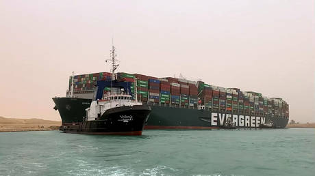 A tugboat pictured in front of the Ever Given lodged sideways in the Suez Canal.