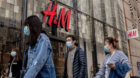 People walk past a store of Swedish clothing giant H&M in Beijing on March 25, 2021. © AFP / NICOLAS ASFOURI