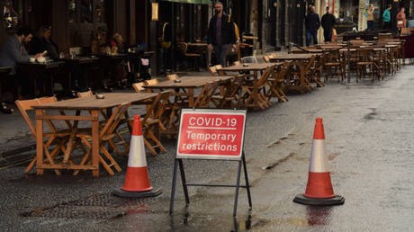 FILE PHOTO. Covid-19 Temporary Restrictions street sign and empty tables in Old Compton Street, Soho. New restrictions have led to fewer customers visiting restaurants and bars in London. © Getty Images / VV Shots