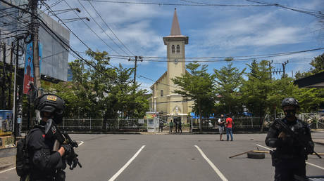 Police officers stand guard outside a church after an explosion in Makassar, Indonesia, March 28, 2021. © Indra Abriyanto / AFP