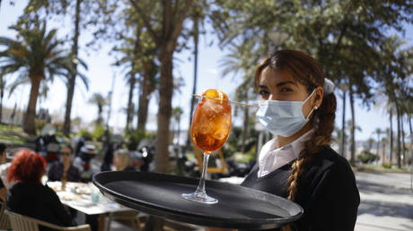 Fiorella, who works as a waitress at the Enco restaurant, carries a cocktail on her tray. Airlines are planning more flights from Germany to Mallorca for the Easter holidays due to strong demand.