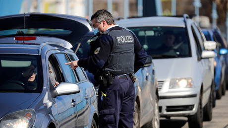 A police officer checks commuters in a car arriving from Poland, at the German-Polish border crossing Stadtbruecke (city bridge) amid the coronavirus disease (COVID-19) outbreak, in Frankfurt (Oder), Germany, March 22, 2021.