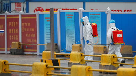 FILE PHOTO. Workers in PPE spray the ground with diinfectant in Baishazhou market during a visit of WHO team in Wuhan, China.