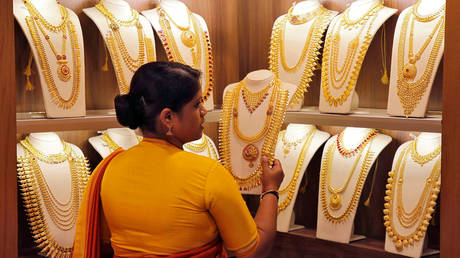A saleswoman picks gold necklaces to show it to a customer inside a jewellery showroom in India