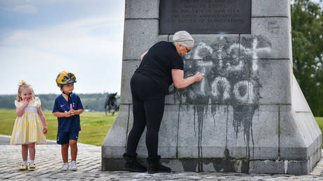 FILE PHOTO: Children look on as a member of the public cleans the Robert the Bruce Statue which has been defaced with graffiti saying "Racist King" on June 12, 2020 in Bannockburn, Scotland