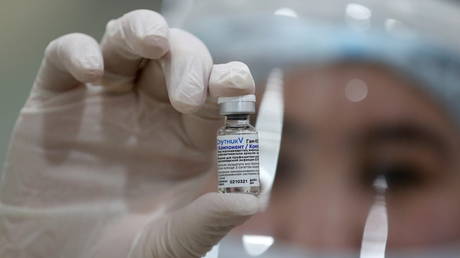 A medical worker poses for a picture while holding a vial with Sputnik V (Gam-COVID-Vac) vaccine against the coronavirus. © Reuters / Pavel Mikheyev