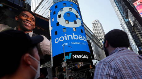 FILE PHOTO: People watch as the logo for Coinbase is displayed on the Nasdaq MarketSite jumbotron at Times Square in New York, US, on April 14, 2021