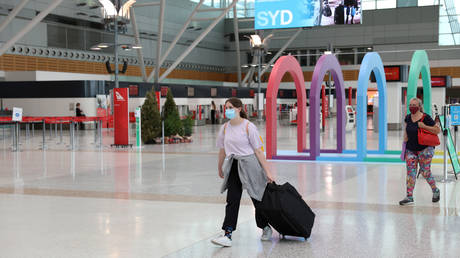 FILE PHOTO. People wearing masks walk through a mostly empty domestic terminal at Sydney Airport.