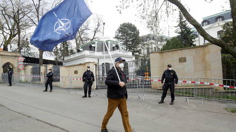 A man carrying a NATO flag outside the Russian Embassy in Prague, Czech Republic on April 18, 2021 © Reuters / David W Cerny