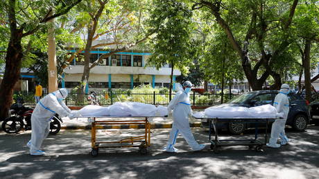 Health workers wearing personal protective equipment carry bodies of people outside a hospital in New Delhi, India on April 24, 2021.