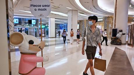 A shopper walks past a mouse statue in a mask in a shopping mall in Bangkok, Thailand on April 26, 2021. © Lillian Suwanrumpha / AFP