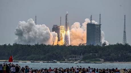 People watch a Long March 5B rocket, carrying China's Tianhe space station core module, as it lifts off from the Wenchang Space Launch Center in southern China's Hainan province on April 29, 2021.