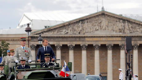 FILE PHOTO: France's President Emmanuel Macron and French Armies Chief Staff General Francois Lecointre stand in the command car as they review troops before the start of the Bastille Day military parade in Paris, France July 14, 2020