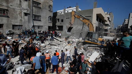 Rescue workers search for victims amid rubble at the site of Israeli air strikes, in Gaza City on May 16, 2021.