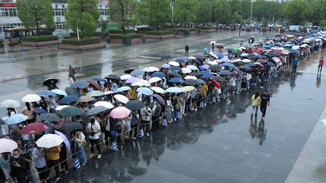 People queue in the rain to get vaccinated against the coronavirus disease (Covid-19), outside a vaccination site in Fuyang, Anhui province, China (FILE PHOTO) © China Daily via REUTERS