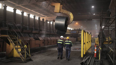 Workers remove a coil from the production line for quality-control testing during steel production at steel mill.