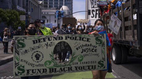 FILE PHOTO. Protesters march with a banner mocking a dollar bill that reads ‘Defund police, Fund black youth’ during a rally to mark Juneteenth in San Francisco, California. © AFP / VIVIAN LIN