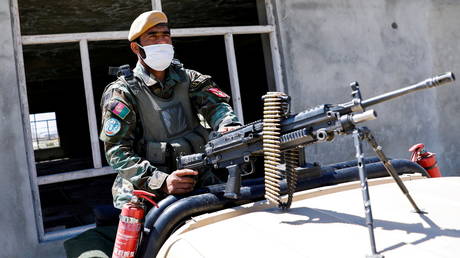 An Afghan National Army soldier sits on a back of an army vehicle at a checkpoint on the outskirts of Kabul