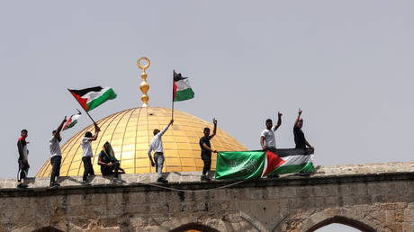 Palestinians hold flags as they stand at the compound that houses Al-Aqsa Mosque in Jerusalem's Old City