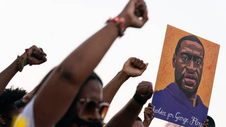 People raise their fists and hold a portrait of George Floyd during a rally following the guilty verdict the trial of Derek Chauvin on April 20, 2021, in Atlanta, Georgia. © Elijah Nouvelage / AFP