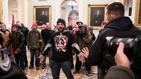 A supporter of President Donald Trump wearing a QAnon shirt confronts police at the US Capitol in Washington DC, January 6, 2021 © Reuters / Mike Theiler