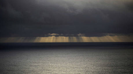 FILE PHOTO. The sun shines through the clouds onto the Pacific Ocean.