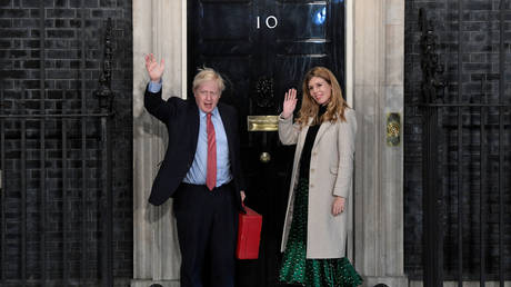 FILE PHOTO. Britain's Prime Minister Boris Johnson and his partner Carrie Symonds gesture as they arrive at 10 Downing Street. © Reuters / Toby Melville