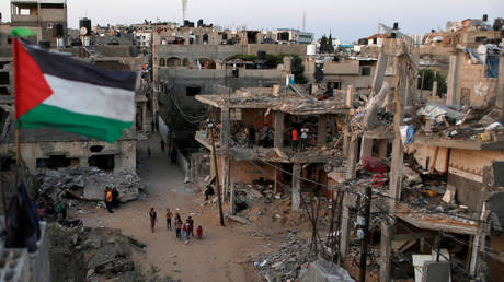 A Palestinian flag flies as the ruins of houses, which were destroyed by Israeli air strikes during the Israeli-Palestinian fighting. © Reuters