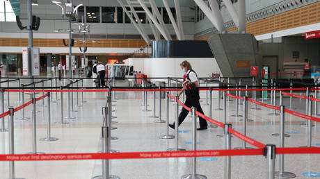 A person walks through a terminal at Sydney Airport in Sydney, Australia, December 2020. © Loren Elliott / Reuters