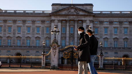 People wearing face masks walk past Buckingham Palace amid the coronavirus disease (COVID-19). © REUTERS / John Sibley