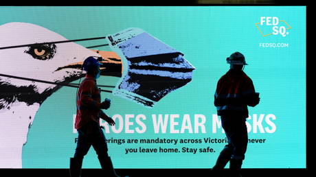 FILE PHOTO: Workers walk past a 'Heroes Wear Masks' sign on the first day of a seven-day statewide lockdown, in Melbourne, Australia, May 28, 2021.