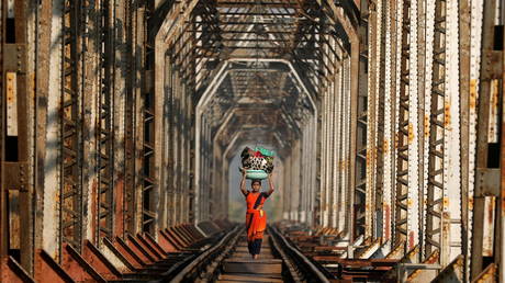 Woman carrying luggage walks along a railway track on the outskirts of Mumbai. © Reuters / Francis Mascarenhas