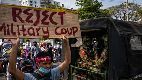 Protesters marching past Myanmar military soldiers who arrived to guard the Central Bank overnight on February 15, 2021 in Yangon, Myanmar